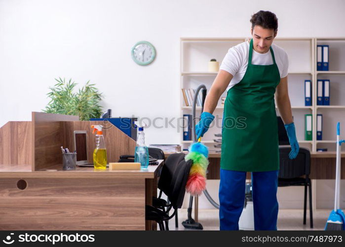 The young handsome contractor cleaning the office . Young handsome contractor cleaning the office