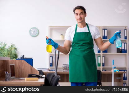 The young handsome contractor cleaning the office. Young handsome contractor cleaning the office