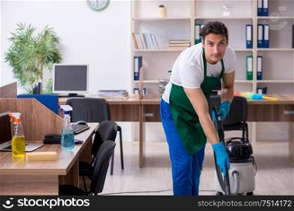 The young handsome contractor cleaning the office. Young handsome contractor cleaning the office