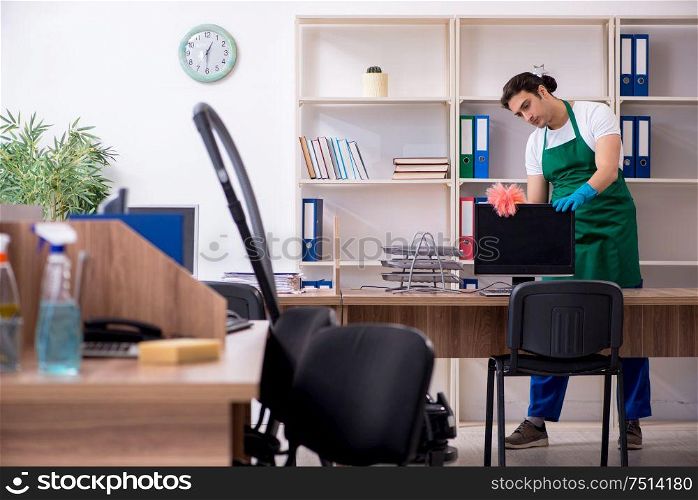 The young handsome contractor cleaning the office. Young handsome contractor cleaning the office