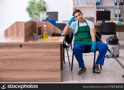 The young handsome contractor cleaning the office. Young handsome contractor cleaning the office