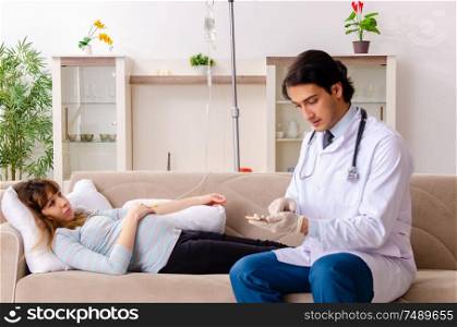 The young handsome doctor visiting pregnant woman at home. Young handsome doctor visiting pregnant woman at home
