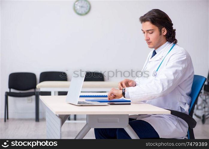 The young handsome doctor working in the clinic . Young handsome doctor working in the clinic