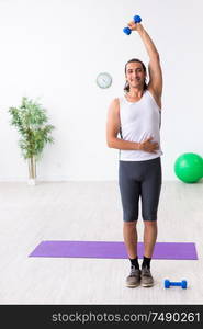 The young handsome man doing sport exercises indoors. Young handsome man doing sport exercises indoors