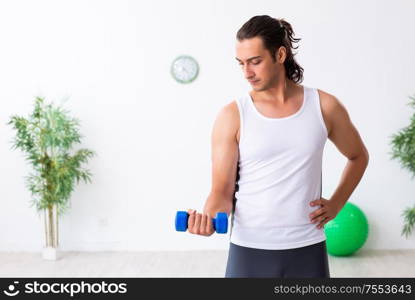 The young handsome man doing sport exercises indoors. Young handsome man doing sport exercises indoors