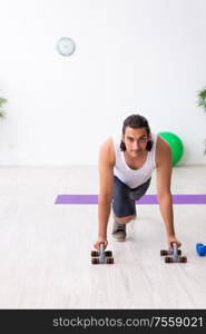 The young handsome man doing sport exercises indoors. Young handsome man doing sport exercises indoors