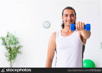 The young handsome man doing sport exercises indoors. Young handsome man doing sport exercises indoors