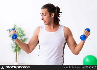 The young handsome man doing sport exercises indoors. Young handsome man doing sport exercises indoors