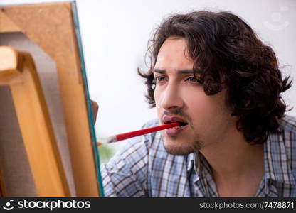 The young handsome man enjoying painting at home. Young handsome man enjoying painting at home