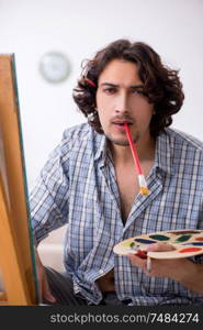 The young handsome man enjoying painting at home. Young handsome man enjoying painting at home