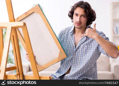 The young handsome man enjoying painting at home. Young handsome man enjoying painting at home