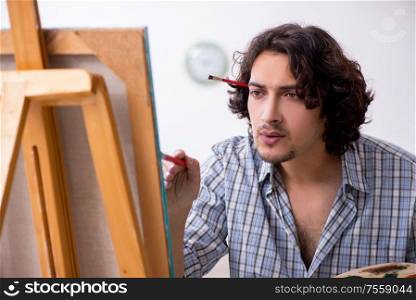 The young handsome man enjoying painting at home. Young handsome man enjoying painting at home