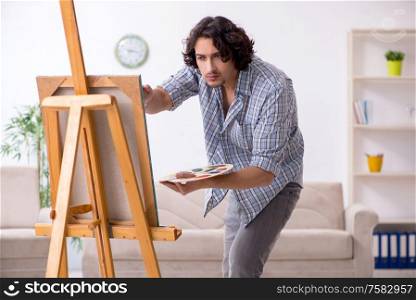 The young handsome man enjoying painting at home. Young handsome man enjoying painting at home