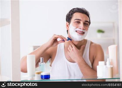 The young handsome man shaving early in the morning at home. Young handsome man shaving early in the morning at home. The young handsome man shaving early in the morning at home