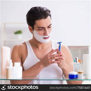 The young handsome man shaving early in the morning at home. Young handsome man shaving early in the morning at home