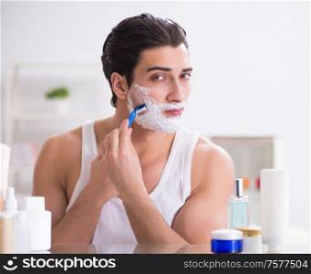 The young handsome man shaving early in the morning at home. Young handsome man shaving early in the morning at home