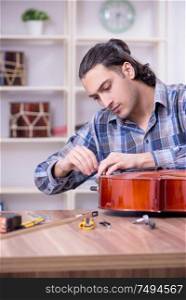 The young handsome repairman repairing cello. Young handsome repairman repairing cello