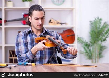 The young handsome repairman repairing violin. Young handsome repairman repairing violin
