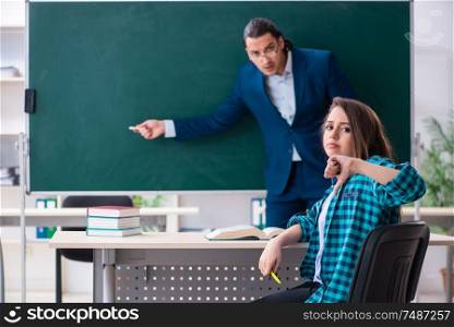 The young handsome teacher and female student in the classroom . Young handsome teacher and female student in the classroom