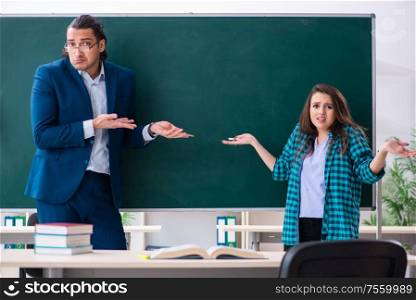 The young handsome teacher and female student in the classroom. Young handsome teacher and female student in the classroom