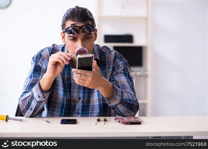 The young handsome technician repairing mobile phone. Young handsome technician repairing mobile phone