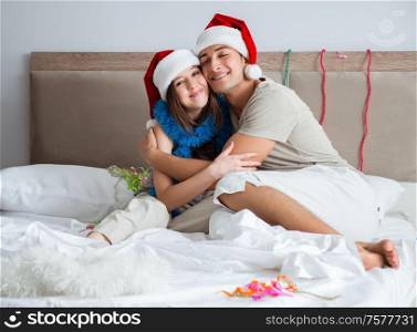 The young happy family celebrating christmas in bed. Young happy family celebrating christmas in bed