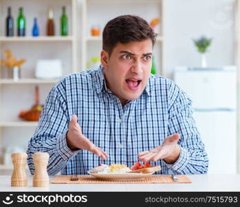 The young husband eating tasteless food at home for lunch. Young husband eating tasteless food at home for lunch