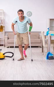 The young injured man cleaning the house. Young injured man cleaning the house