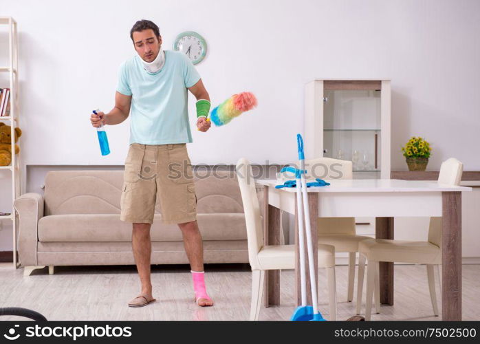 The young injured man cleaning the house. Young injured man cleaning the house