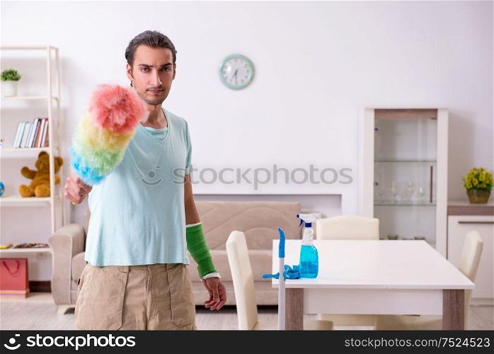 The young injured man cleaning the house. Young injured man cleaning the house