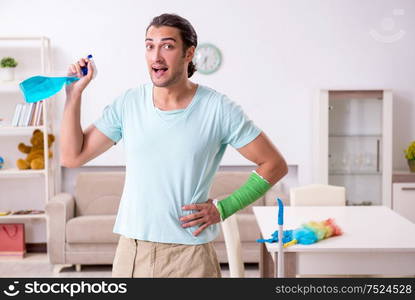 The young injured man cleaning the house. Young injured man cleaning the house