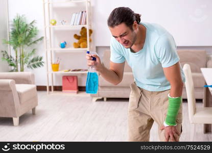 The young injured man cleaning the house. Young injured man cleaning the house