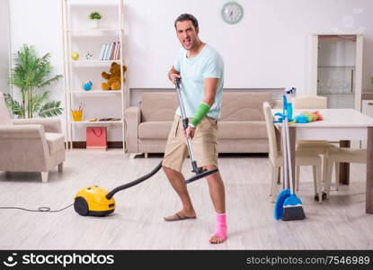The young injured man cleaning the house. Young injured man cleaning the house