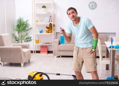 The young injured man cleaning the house. Young injured man cleaning the house