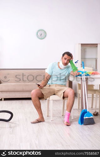 The young injured man cleaning the house. Young injured man cleaning the house