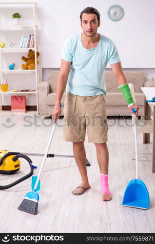 The young injured man cleaning the house. Young injured man cleaning the house