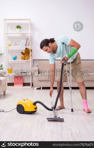 The young injured man cleaning the house. Young injured man cleaning the house