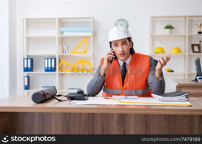 The young male architect working in the office . Young male architect working in the office