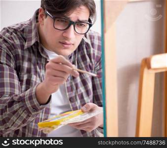 The young male artist drawing pictures in bright studio. Young male artist drawing pictures in bright studio