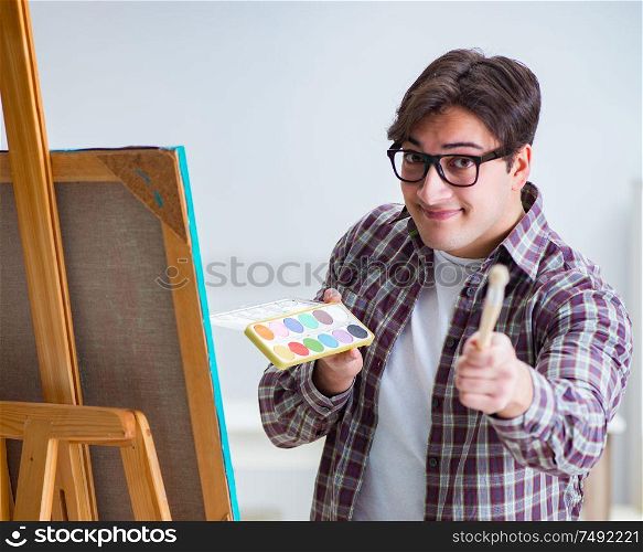 The young male artist drawing pictures in bright studio. Young male artist drawing pictures in bright studio