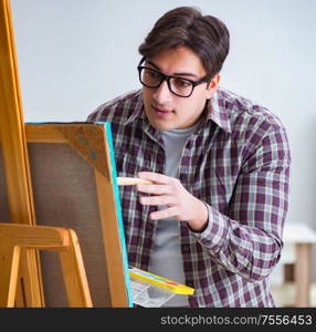 The young male artist drawing pictures in bright studio. Young male artist drawing pictures in bright studio