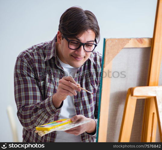 The young male artist drawing pictures in bright studio. Young male artist drawing pictures in bright studio