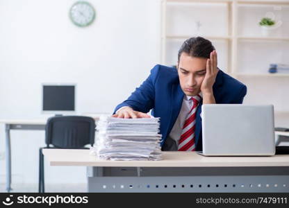 The young male businessman sitting in the office . Young male businessman sitting in the office