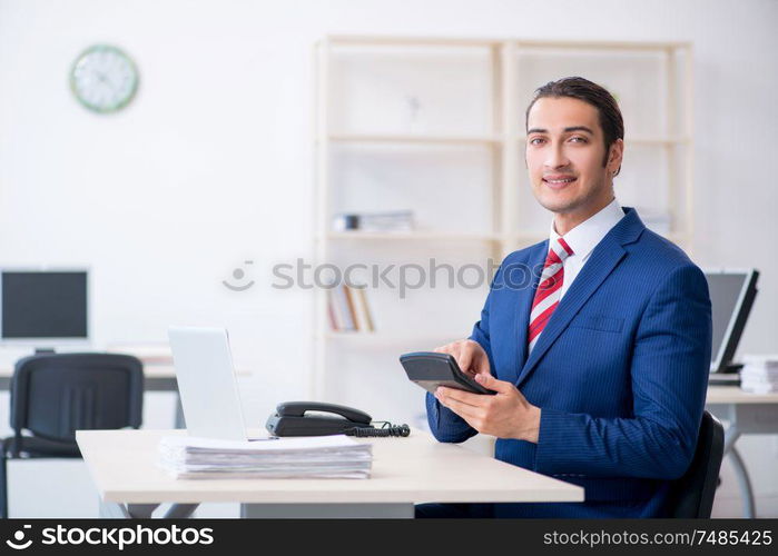 The young male businessman sitting in the office . Young male businessman sitting in the office