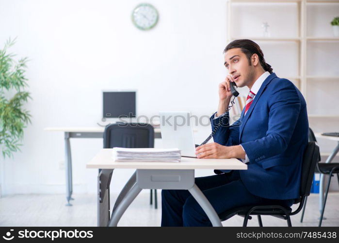 The young male businessman sitting in the office . Young male businessman sitting in the office