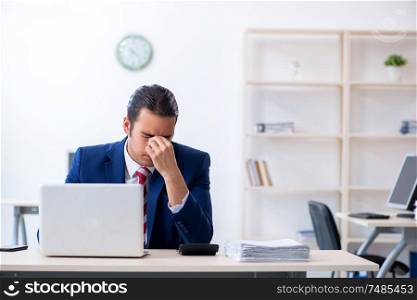 The young male businessman sitting in the office . Young male businessman sitting in the office