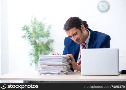 The young male businessman sitting in the office . Young male businessman sitting in the office