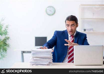 The young male businessman sitting in the office . Young male businessman sitting in the office