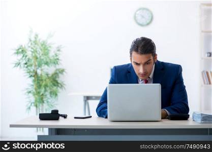 The young male businessman sitting in the office. Young male businessman sitting in the office