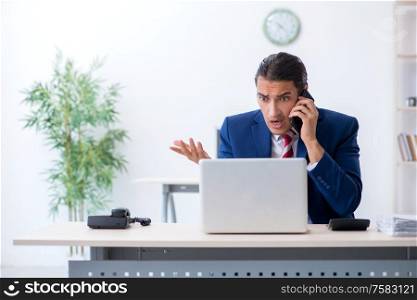 The young male businessman sitting in the office. Young male businessman sitting in the office